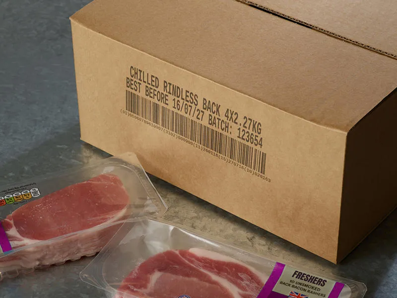 A porous cardboard box with a Cx150i code printed on the outside and some packets of bacon nearby.